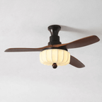 Ribbed cream lantern shade and dark walnut blades appear in close view against a plain grey background, on this Clérachic ceiling fan.