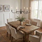 Above a rustic wood table set for a meal, this Clérachic chandelier in matte black lights a dining room with wainscoted walls.