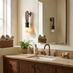 Mirrored above a stone vanity counter, this Clérachic wall light hangs beside a small potted fern.