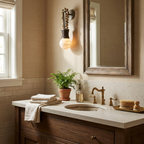 Near a wood-framed mirror and a potted fern, this Clérachic wall light lights a vanity with brass fixtures.