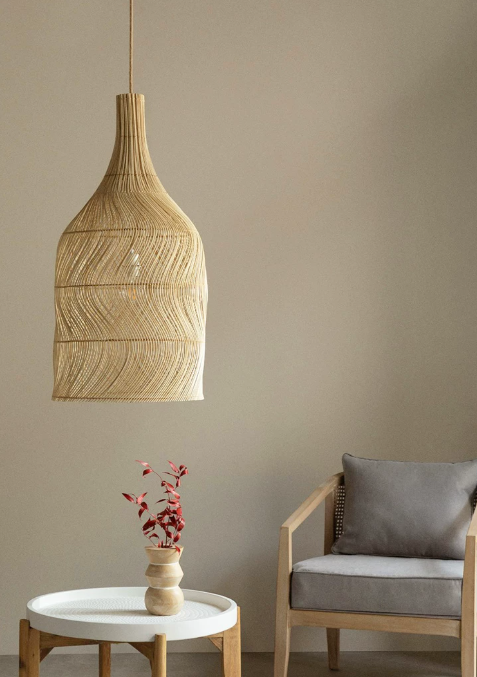 In a room corner, this Clérachic pendant hangs beside a grey armchair and a small round side table.