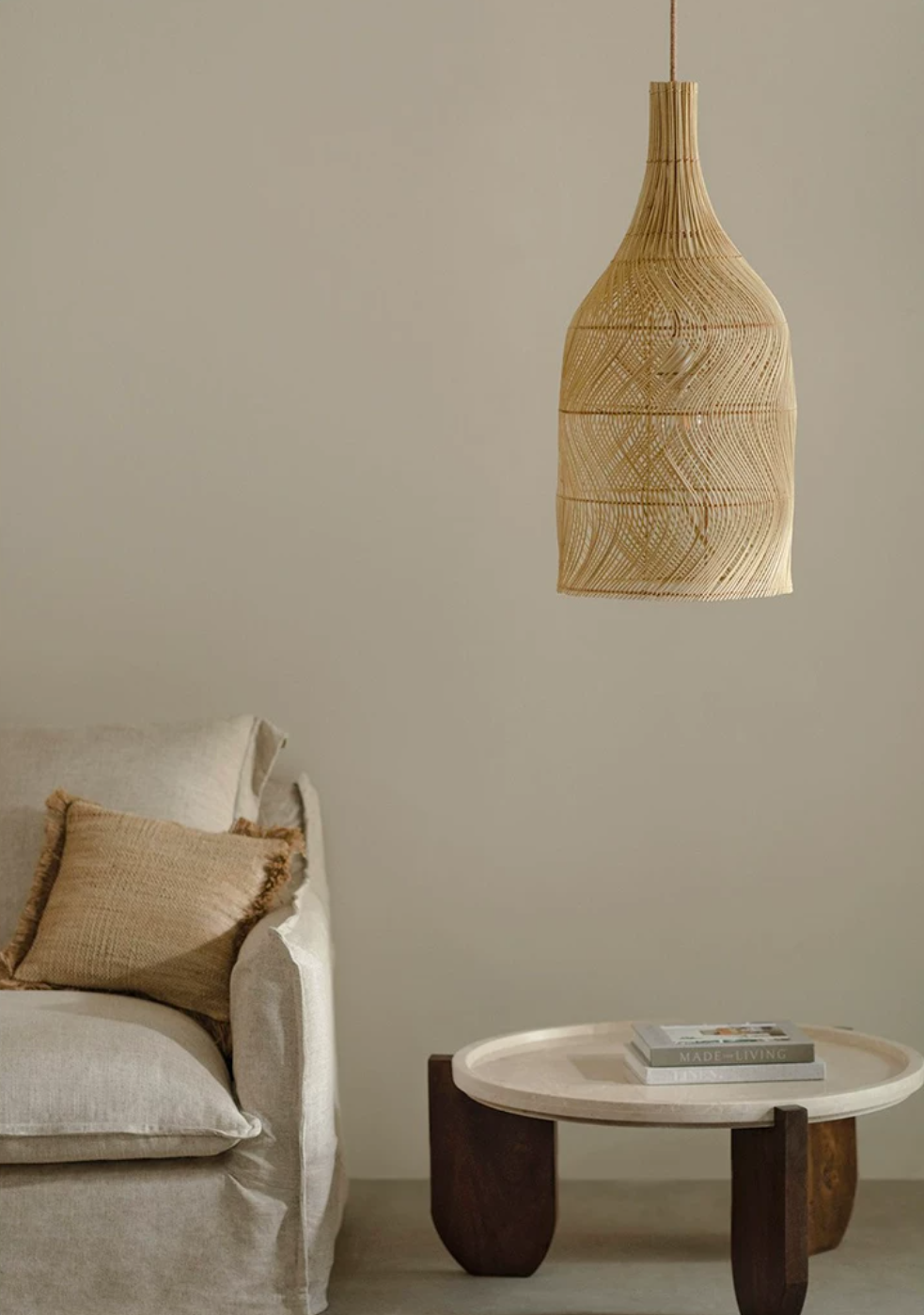 This Clérachic pendant hangs beside a linen sofa with a jute cushion and a round stone-topped table.