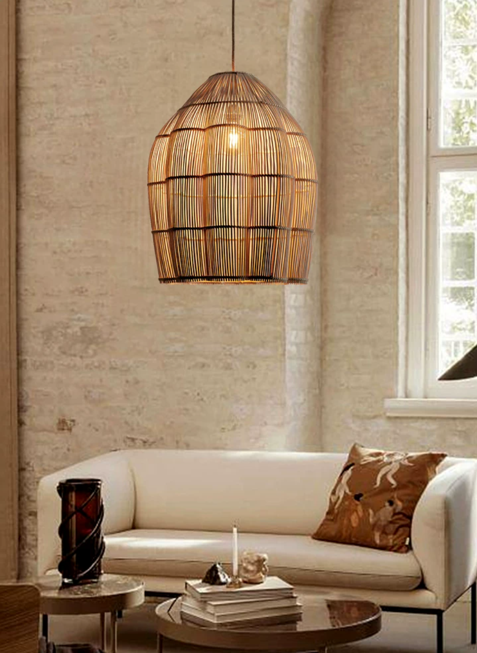 In a brick-walled room, this Clérachic pendant glows warmly above a cream sofa with a patterned cushion.