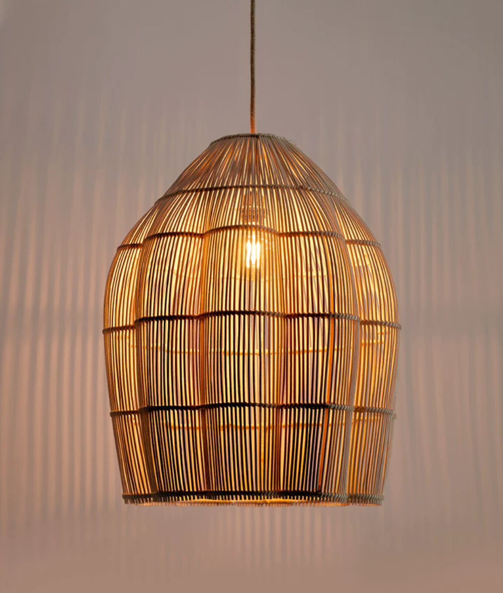 Close lit view of this Clérachic pendant, its warm glow showing through the vertical rattan ribs.