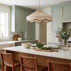 In a kitchen with muted-green cabinetry, this Clérachic pendant's pleated beige shade hangs above a marble island.