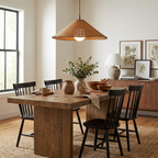 This Clérachic pendant lights a wood dining table set beside a sideboard with a lamp and framed art.