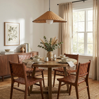 Woven leather chairs and a sideboard with botanical art sit beneath this lit Clérachic pendant.