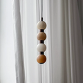 Close view of four pale alabaster spheres at the top of this Clérachic pendant against a curtain.