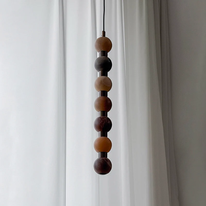 The mid-section of this Clérachic pendant shows dark brown and cream stone tones against a curtain.