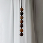 The mid-section of this Clérachic pendant shows dark brown and cream stone tones against a curtain.