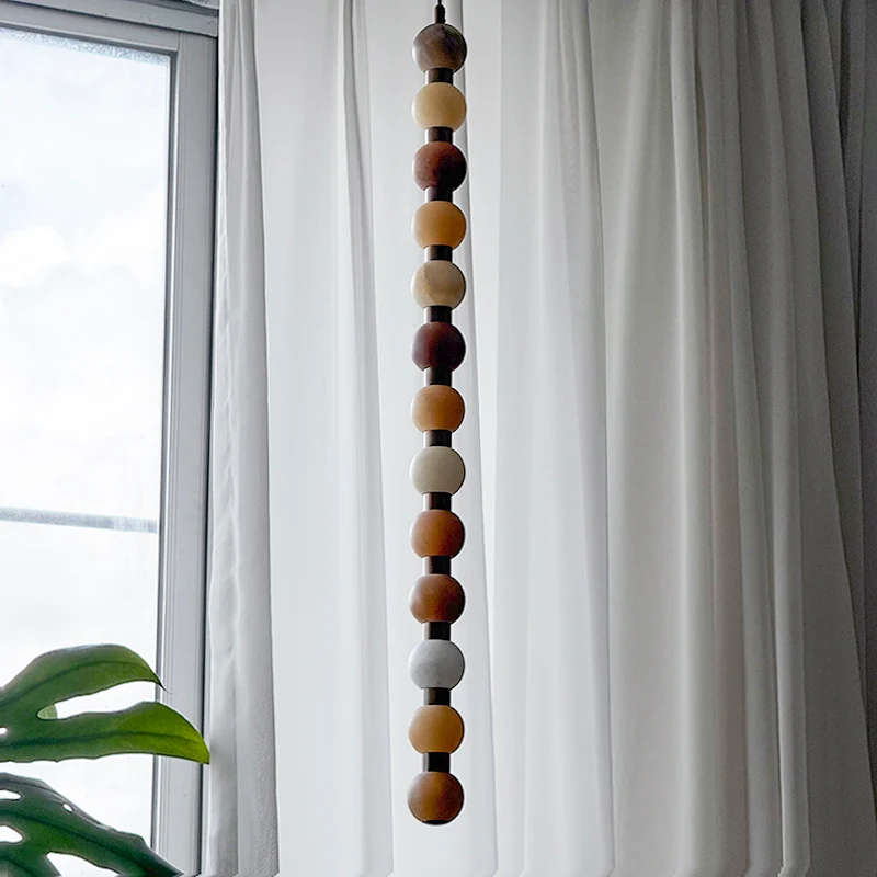 The full length of this Clérachic pendant shows its natural stone colour variation against a window.