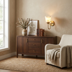 This brushed brass Clérachic wall sconce glows above a walnut console dressed with books and a framed botanical print.