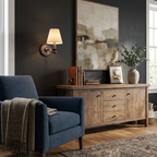 Beside an abstract painting, this matte black Clérachic wall sconce glows above a wood sideboard and a navy armchair.