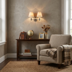 This brushed nickel Clérachic wall sconce glows above a dark wood console dressed with books and a globe.