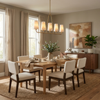 Near curtained windows and an abstract print, this Clérachic chandelier in brushed brass hangs over cream dining chairs.