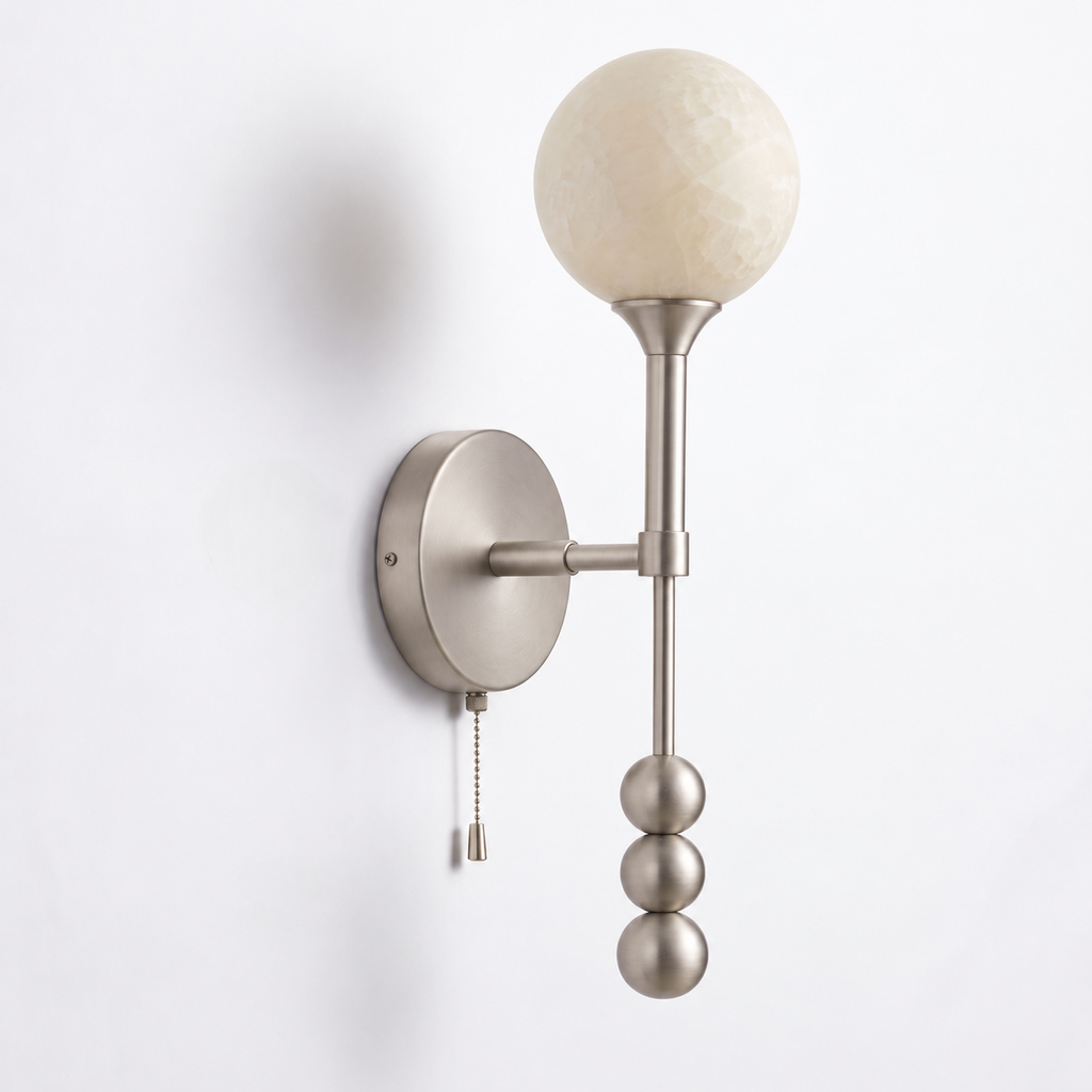 Side view of this Clérachic wall sconce in brushed nickel, its three stacked metal balls hanging below the mount.