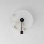 This Clérachic wall sconce in matte black shows the alabaster disc's natural veining, unlit on a plain backdrop.