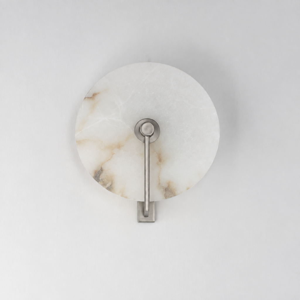 This Clérachic wall sconce in brushed nickel shows its diagonal arm against the alabaster disc's veining.