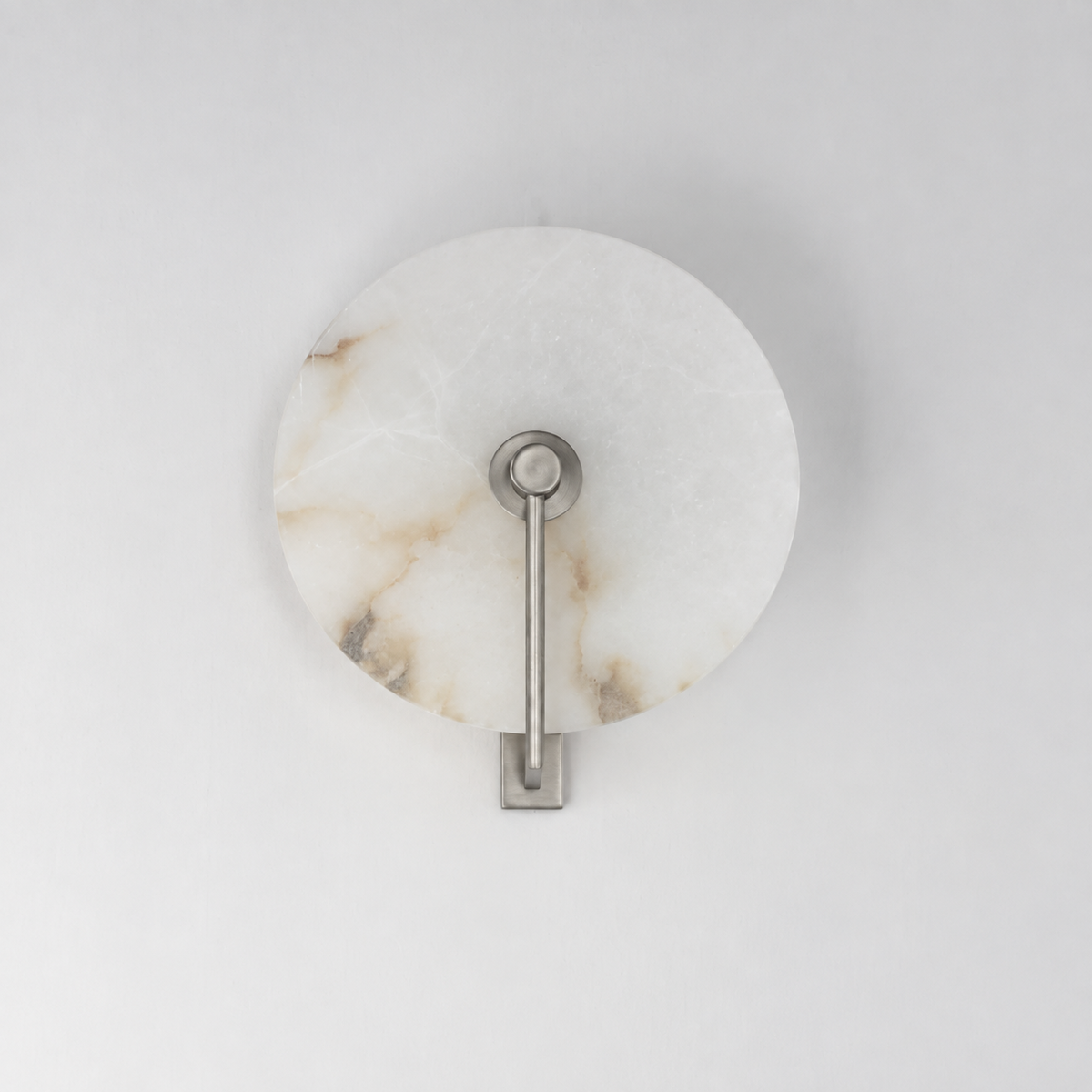 This Clérachic wall sconce in brushed nickel shows its diagonal arm against the alabaster disc's veining.