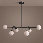 This Clérachic chandelier in matte black is shown face-on, its curved arms holding staggered alabaster balls.