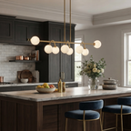 A brushed-brass Clérachic chandelier lights a kitchen island with navy barstools and open shelving.