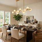 A brushed-brass Clérachic chandelier lights a dining table with beige chairs beneath wood-panelled walls.