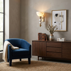 Near a navy-blue armchair, this brass Clérachic sconce lights a console styled with books and framed art.