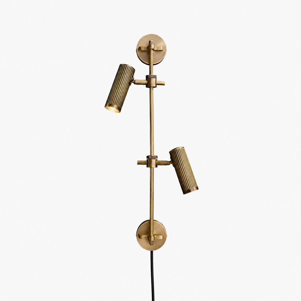 Studio shot of this Clérachic plug-in spotlight in bronze finish, its two ribbed heads mounted along a vertical rail.
