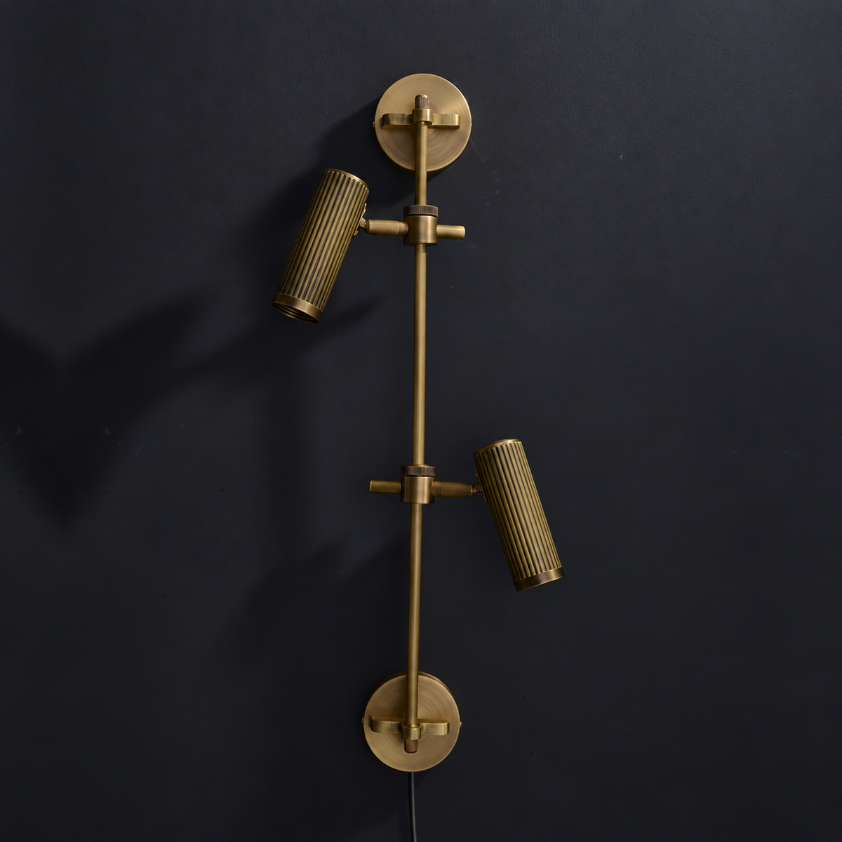 Studio shot of this Clérachic plug-in spotlight in bronze finish against black, its cord visible below.