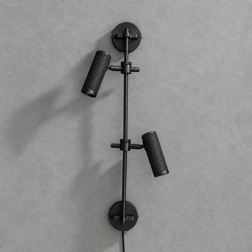 Studio shot of this Clérachic plug-in spotlight in black finish, its two ribbed heads unlit against grey.