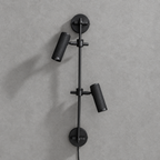 Studio shot of this Clérachic plug-in spotlight in black finish, its two ribbed heads unlit against grey.