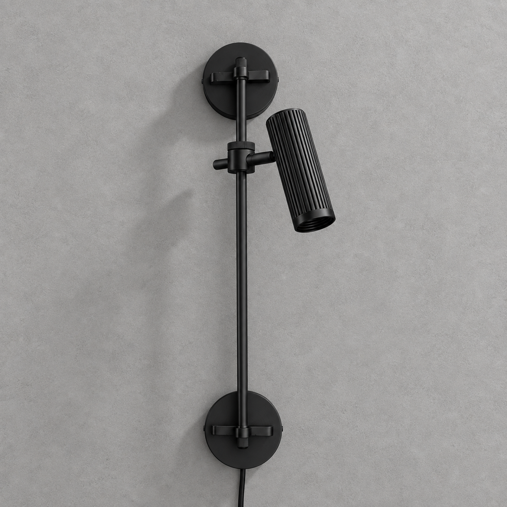 Studio shot of this Clérachic plug-in spotlight in black finish, its cord trailing from the base plate.