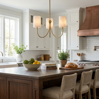 A brass three-arm chandelier from Clérachic hangs above a kitchen island, with a copper range hood behind it.