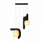 This two-light Clérachic fixture in black appears here in studio, its bent and vertical shades both glowing warm.
