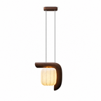 Studio shot of this dark wood, vertical-style Clérachic pendant, its shade glowing warm on a long single cord.