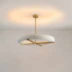 This Clérachic ceiling light in gold casts a warm glowing halo across the ceiling above its oval white shade.