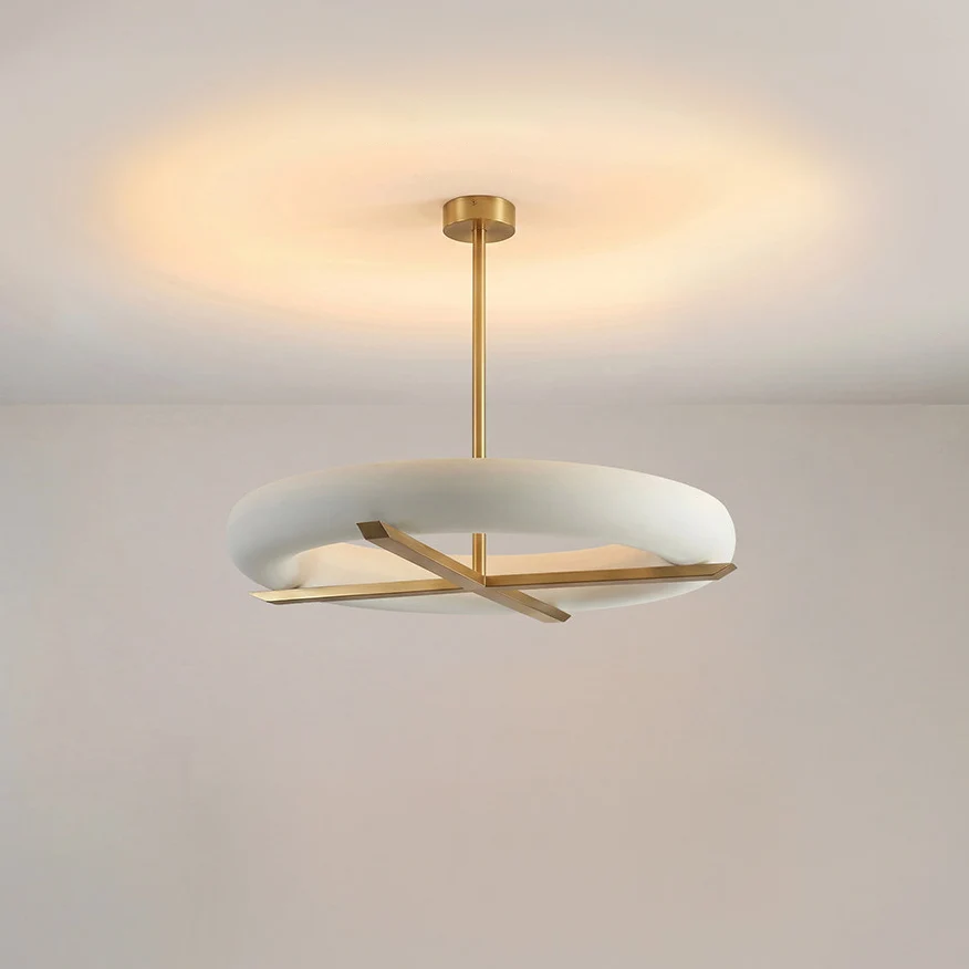 This Clérachic ceiling light in gold casts a warm glowing halo across the ceiling above its oval white shade.