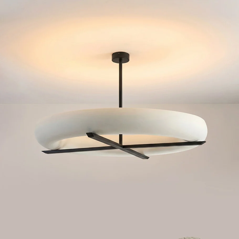 Angled to show its profile, this Clérachic ceiling light in black glows warm beneath a plain grey backdrop.