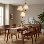 Above a dark wood dining table set for a meal, three of these Clérachic pendants hang near a gallery wall.
