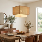 Above a wood dining table with leather-back chairs and a round mirror nearby, this Clérachic pendant glows warm.