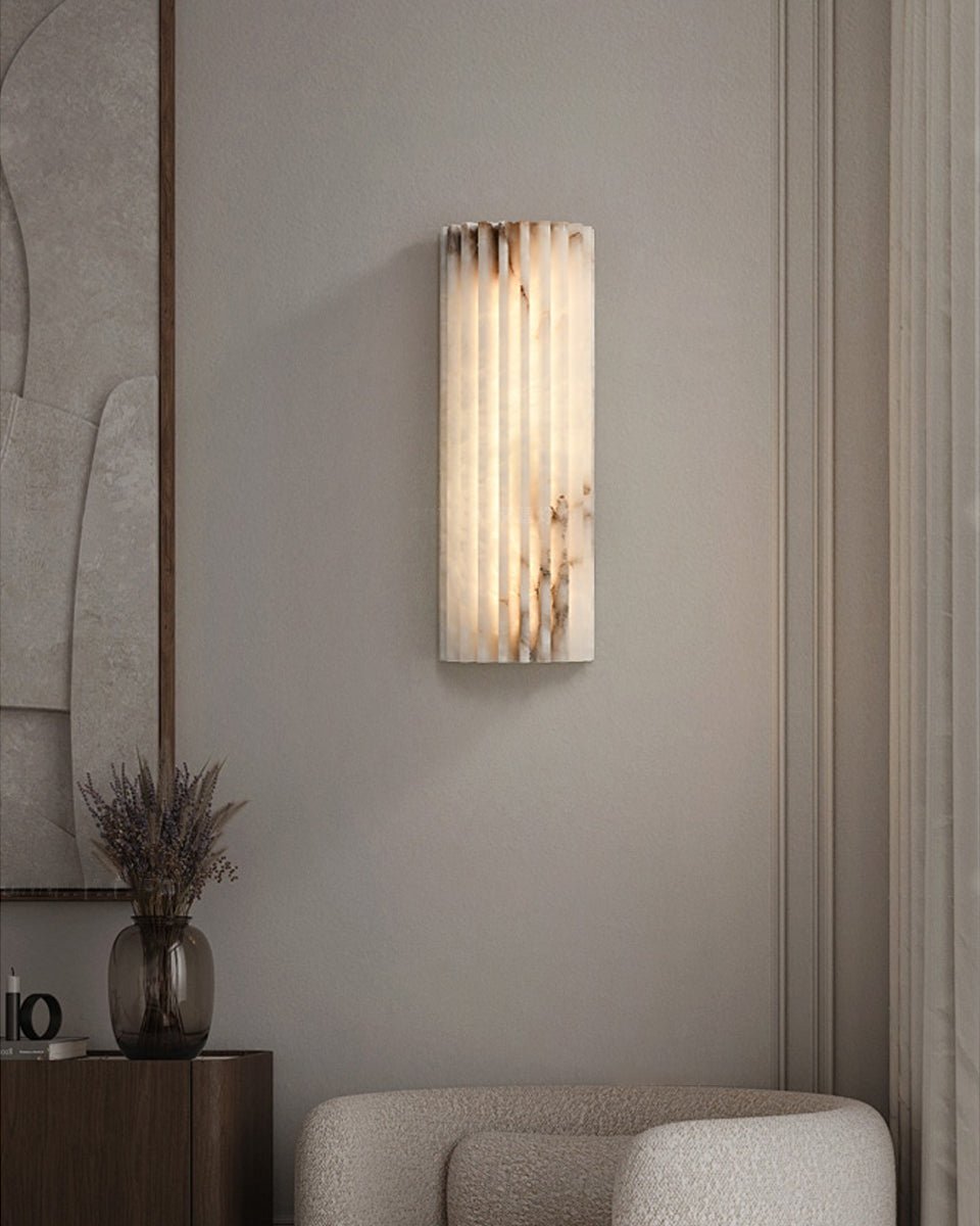 Alabaster wall light lit beside a piece of framed art