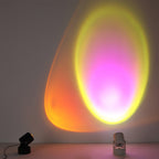 Side by side, a black and a white Clérachic projection lamp cast a yellow and magenta gradient halo on a grey wall.