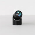 This black Clérachic projection lamp tilts its lens forward, unlit, on a plain light backdrop.