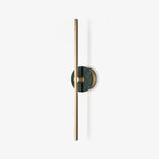 Clérachic wall sconce photographed alone on white, a slim brass bar crossed by a small green stone disc partway up.