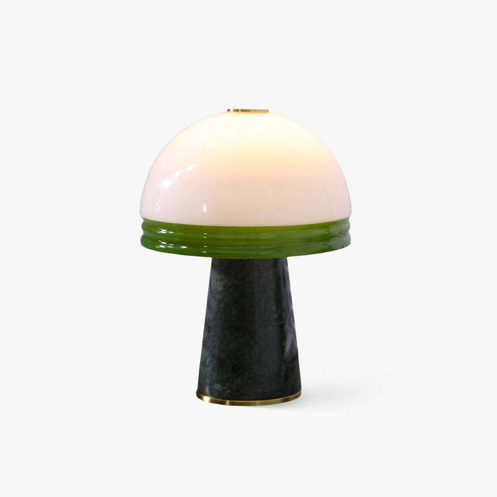 Clérachic table lamp with a glowing white dome shade banded in green glass, set on a dark green marble cone base against a white backdrop.