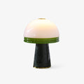 Clérachic table lamp with a glowing white dome shade banded in green glass, set on a dark green marble cone base against a white backdrop.