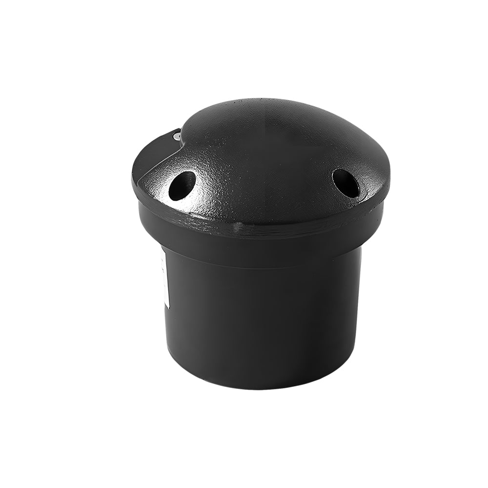 The unlit light on white, its plain black dome and two side openings above the buried canister.