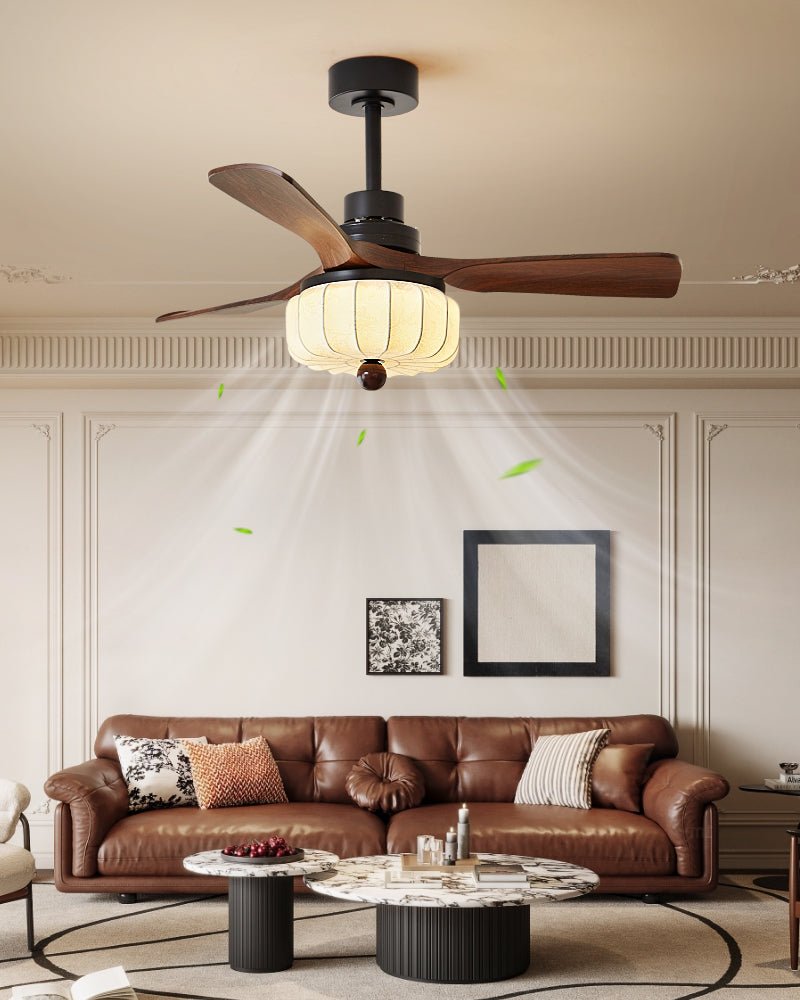 Over a leather sofa and round marble coffee tables, this Clérachic ceiling fan's walnut blades and softly lit lantern shade furnish the living room.