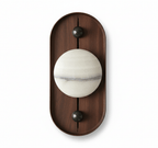 The oval Koyan wall light unlit, its alabaster globe crossed by a grey mineral band, on white.