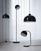 Black dome-shade floor lamp from Clérachic grouped with two matching pendant lights on a white curtain backdrop.